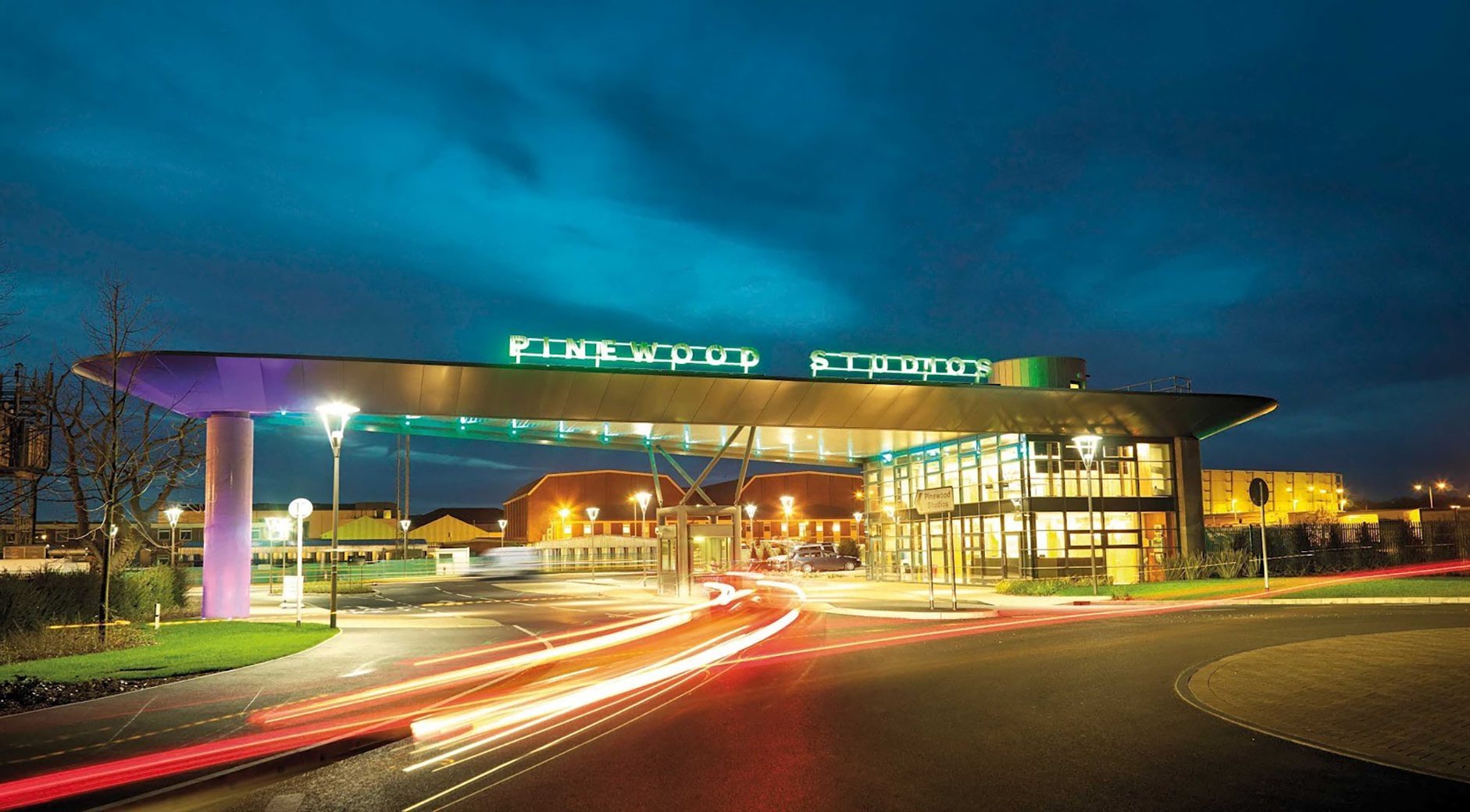The Pinewood Studios entrance gate lit up at dusk